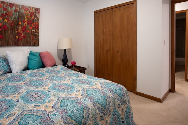 bedroom featuring light carpet, baseboards, and a closet