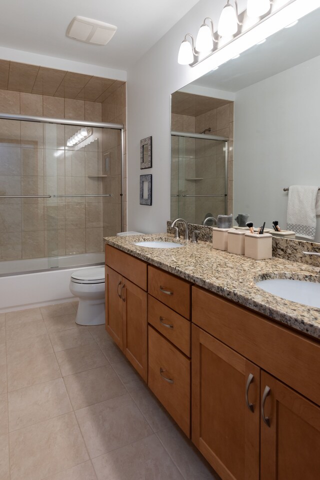 bathroom featuring tile patterned flooring, a sink, toilet, and double vanity