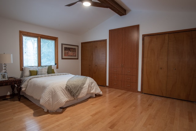 bedroom featuring vaulted ceiling with beams, light wood finished floors, a ceiling fan, and multiple closets