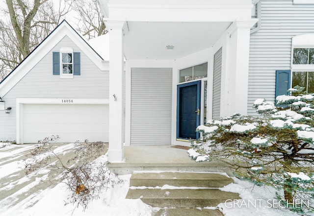 snow covered property entrance with a garage