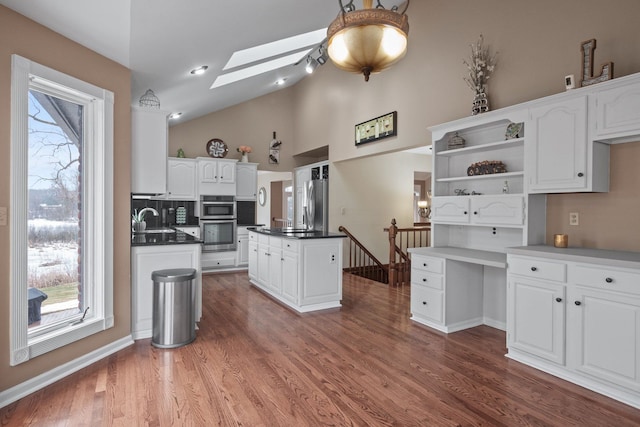 kitchen featuring open shelves, white cabinetry, a skylight, and a sink