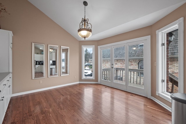 unfurnished dining area featuring baseboards, lofted ceiling, visible vents, and wood finished floors