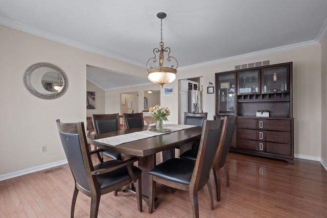 dining space with visible vents, baseboards, and wood finished floors