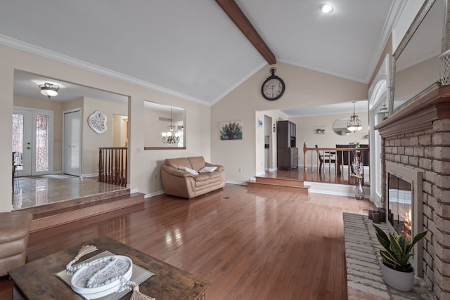 unfurnished living room with lofted ceiling with beams, a notable chandelier, a brick fireplace, and wood finished floors