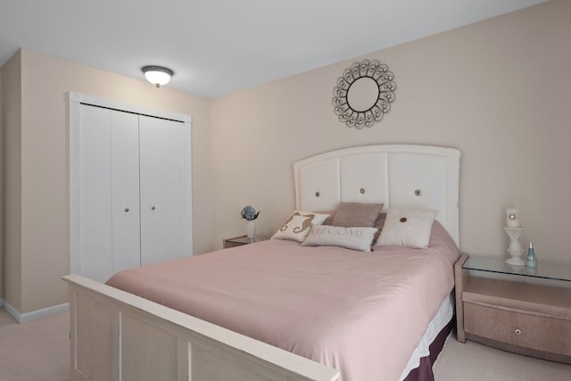 bedroom featuring a closet, light colored carpet, and baseboards