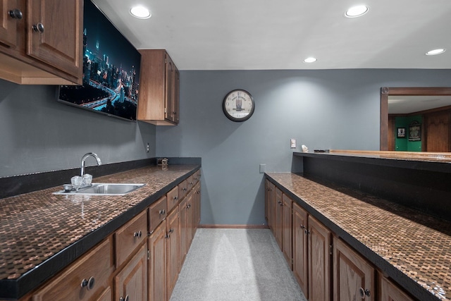 kitchen with light carpet, a sink, dark countertops, recessed lighting, and baseboards