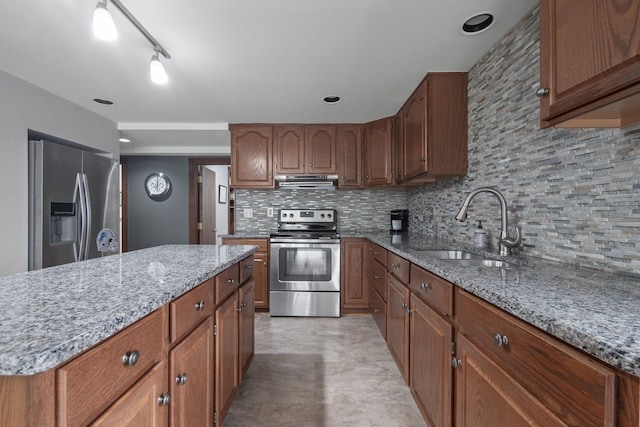 kitchen with a sink, stainless steel appliances, light stone countertops, and tasteful backsplash