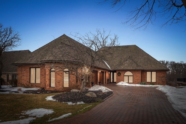 view of front of house with decorative driveway and brick siding