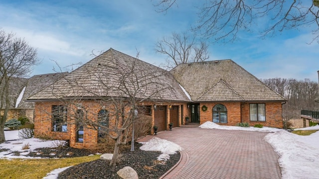 view of front of property with decorative driveway, brick siding, and a garage