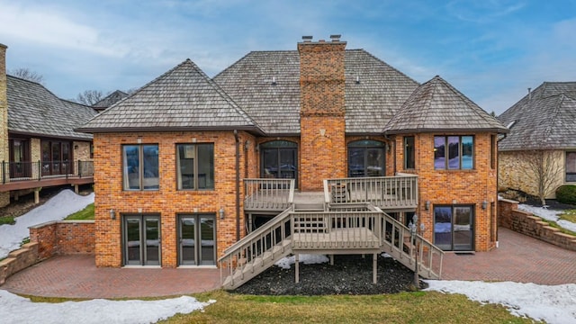 rear view of property with a patio, stairway, a wooden deck, a chimney, and brick siding