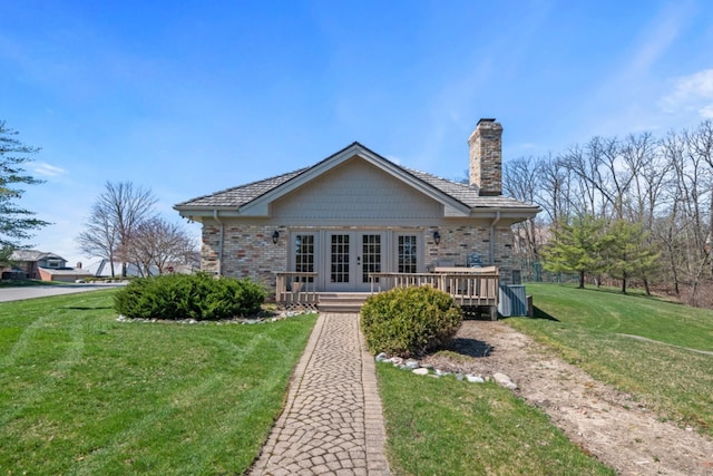 rear view of house with a wooden deck, a chimney, french doors, a lawn, and brick siding