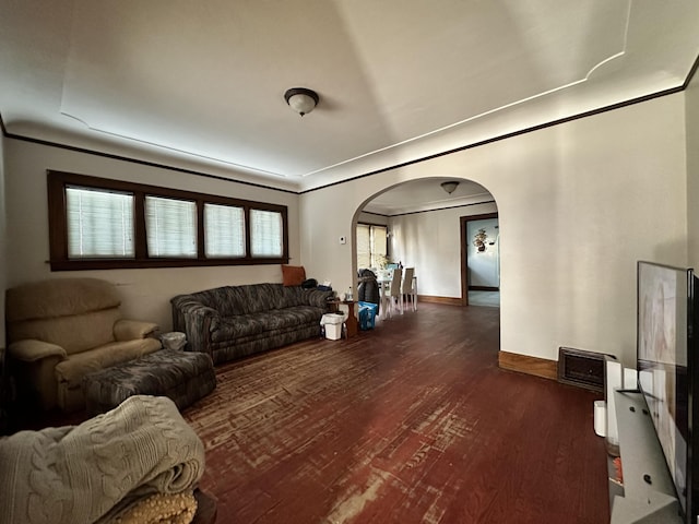 living area with baseboards, arched walkways, dark wood-type flooring, and ornamental molding