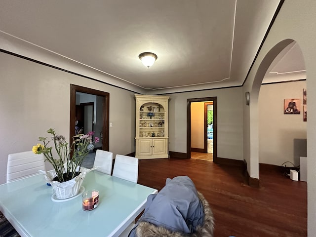 dining space with baseboards, arched walkways, and dark wood-style flooring