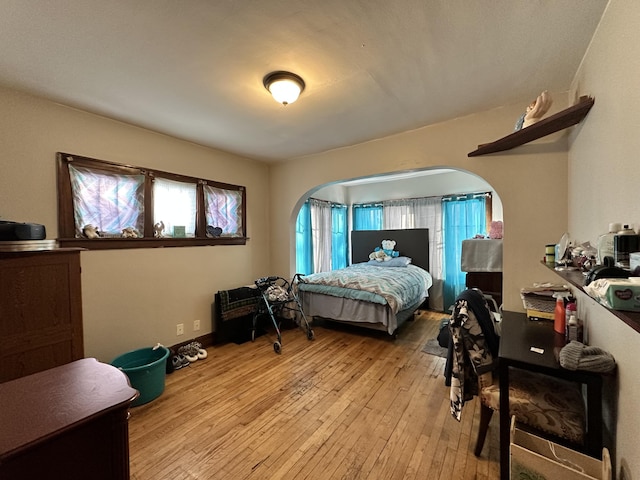 bedroom with light wood-style flooring and arched walkways