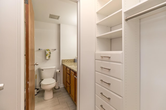 bathroom with visible vents, vanity, and toilet