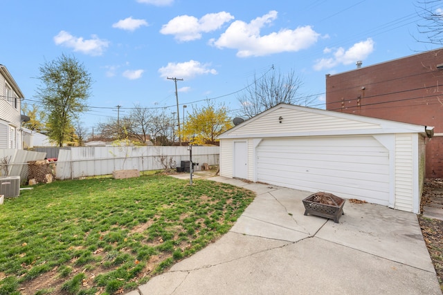 view of yard with a fenced backyard, a fire pit, a garage, an outdoor structure, and driveway