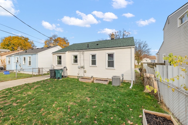 back of property with a vegetable garden, a lawn, a fenced backyard, a chimney, and cooling unit