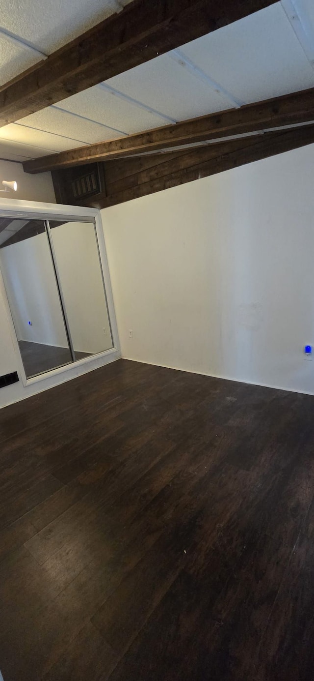 spare room with beamed ceiling, wood finished floors, and visible vents