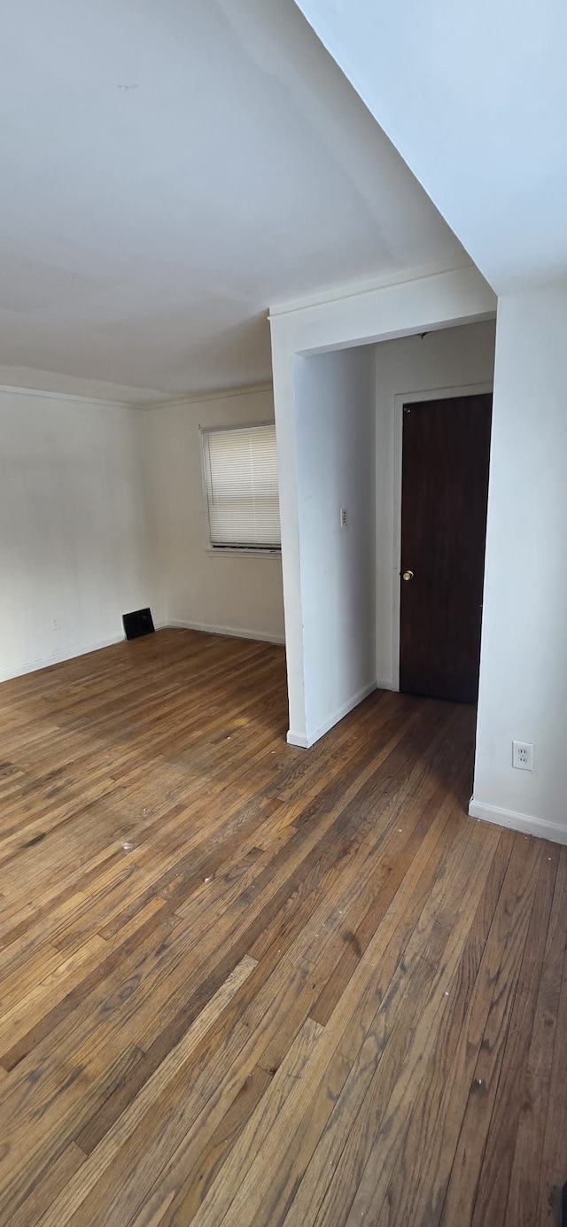 empty room featuring baseboards and dark wood-style flooring