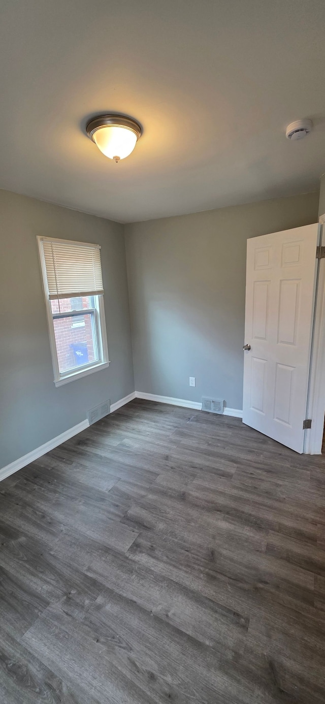 unfurnished bedroom with dark wood-style flooring, visible vents, and baseboards