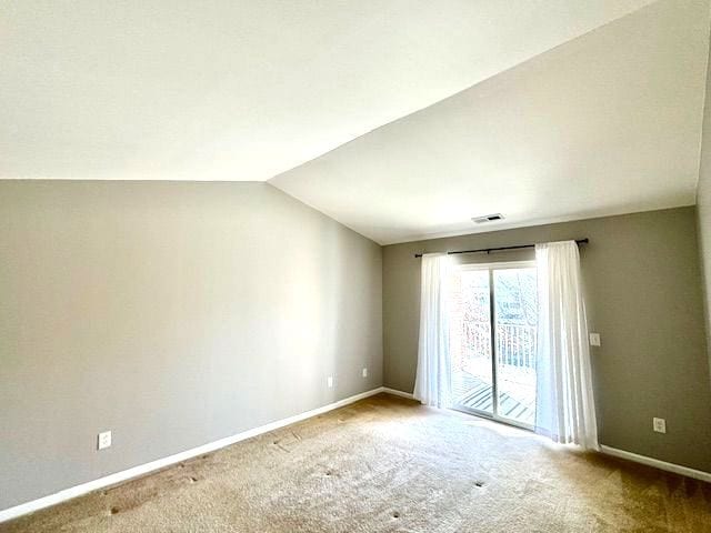 carpeted spare room with lofted ceiling, visible vents, and baseboards