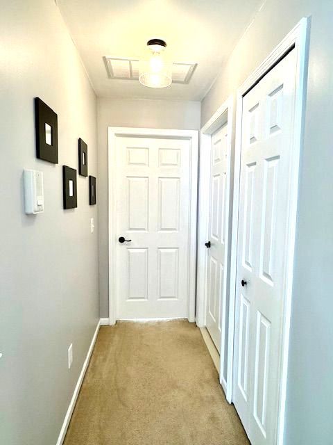 hallway featuring baseboards and light colored carpet