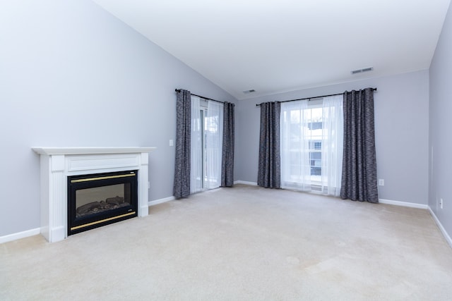 unfurnished living room with light carpet, baseboards, visible vents, a glass covered fireplace, and vaulted ceiling