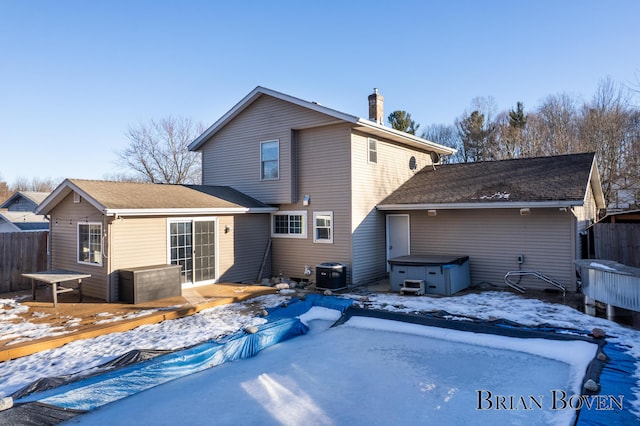 snow covered property with a hot tub, fence, cooling unit, and a wooden deck