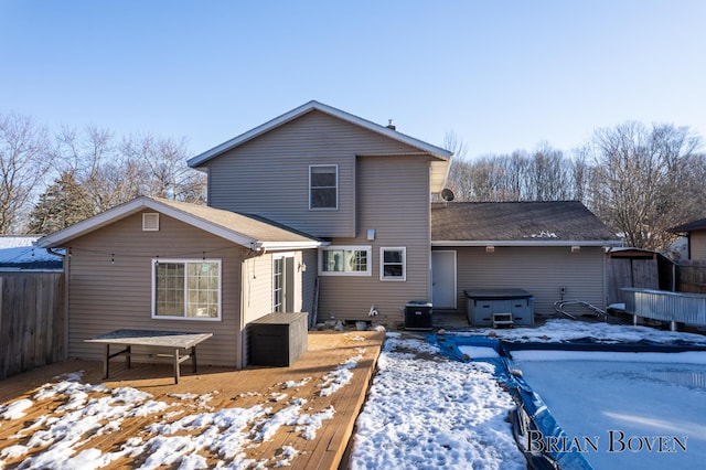 snow covered property with a hot tub, fence, and a wooden deck