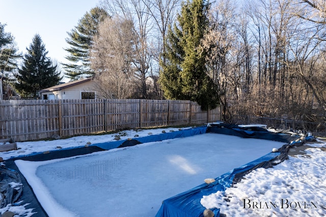 snow covered pool with a fenced backyard