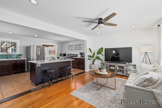 living room with light wood-type flooring, ceiling fan, and recessed lighting