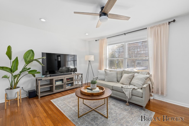 living room with hardwood / wood-style flooring, ceiling fan, and baseboards