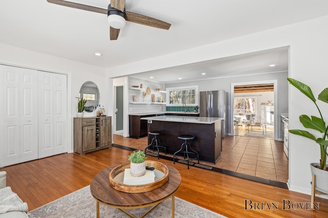 living room with ceiling fan, recessed lighting, baseboards, and light wood-style floors