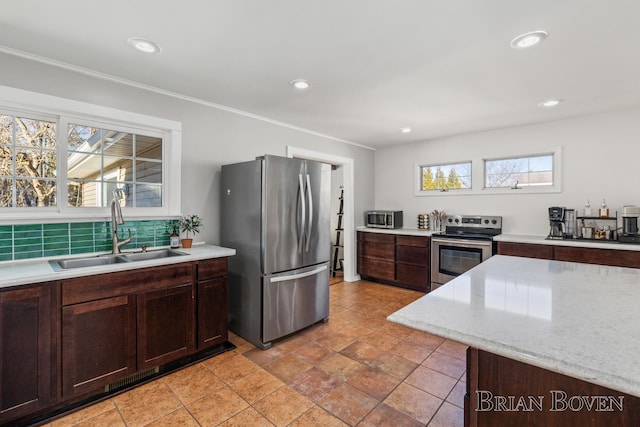 kitchen with tasteful backsplash, recessed lighting, appliances with stainless steel finishes, a sink, and dark brown cabinetry