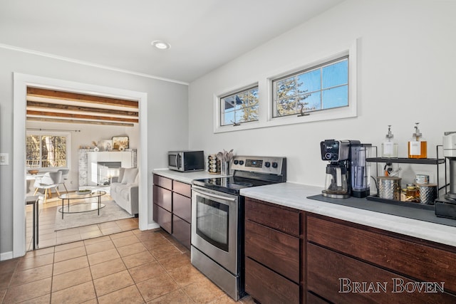 kitchen with light tile patterned floors, stainless steel appliances, dark brown cabinets, light countertops, and a fireplace