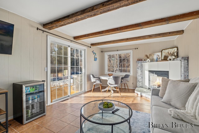 living room featuring light tile patterned floors, wine cooler, wooden walls, a multi sided fireplace, and beamed ceiling