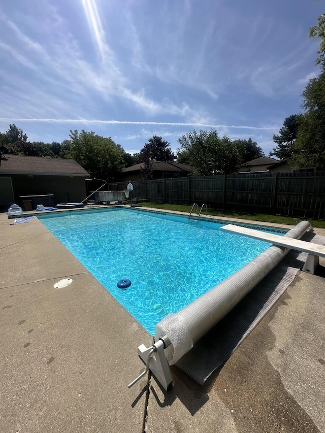 view of pool with a fenced in pool, a fenced backyard, and a diving board