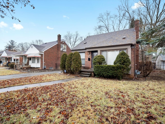 view of front of house with a chimney, a front lawn, and brick siding