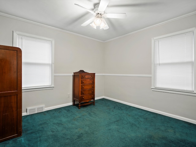 spare room featuring a ceiling fan, visible vents, baseboards, dark colored carpet, and crown molding