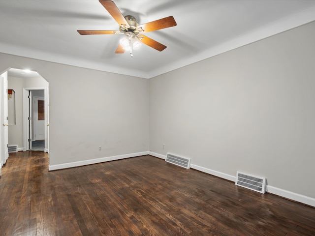 unfurnished room featuring arched walkways, hardwood / wood-style floors, visible vents, and baseboards