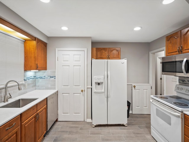 kitchen with decorative backsplash, brown cabinetry, appliances with stainless steel finishes, light countertops, and a sink