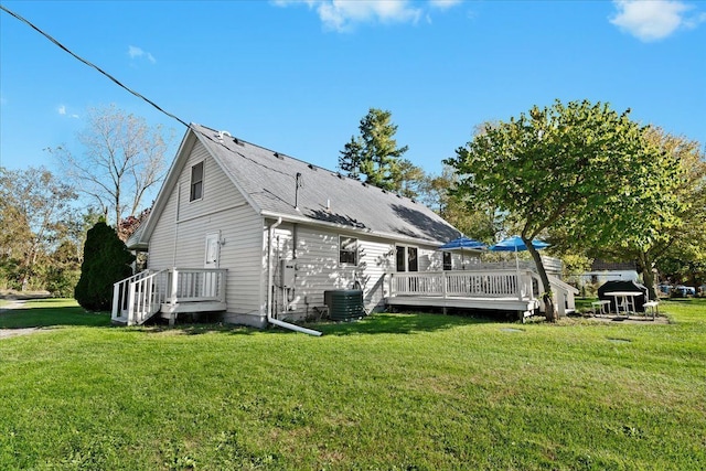 view of side of property featuring a shingled roof, central AC unit, a lawn, and a wooden deck