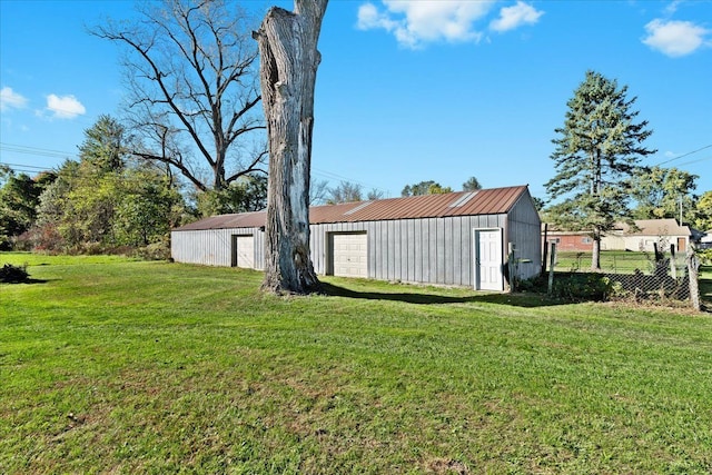 view of yard featuring a detached garage, fence, an outdoor structure, and an outbuilding