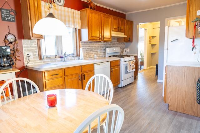 kitchen featuring white appliances, tasteful backsplash, crown molding, under cabinet range hood, and a sink