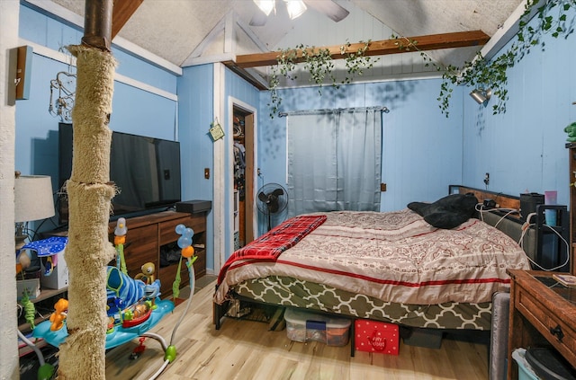 bedroom featuring lofted ceiling, wooden walls, and wood finished floors