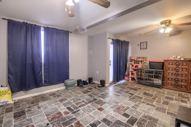 empty room featuring stone finish floor, ceiling fan, and baseboards