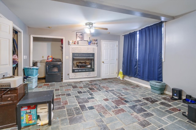 living area featuring ceiling fan, a fireplace, and baseboards