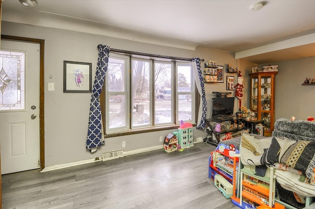 living area featuring visible vents, baseboards, and wood finished floors