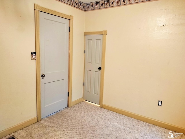 unfurnished room featuring light carpet and baseboards