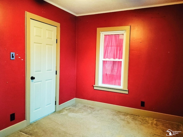 carpeted empty room with crown molding and baseboards